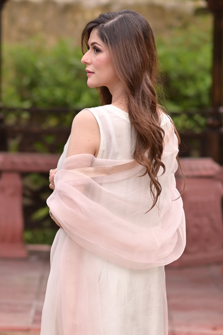 Woman in a light pink saree with a blurred outdoor background