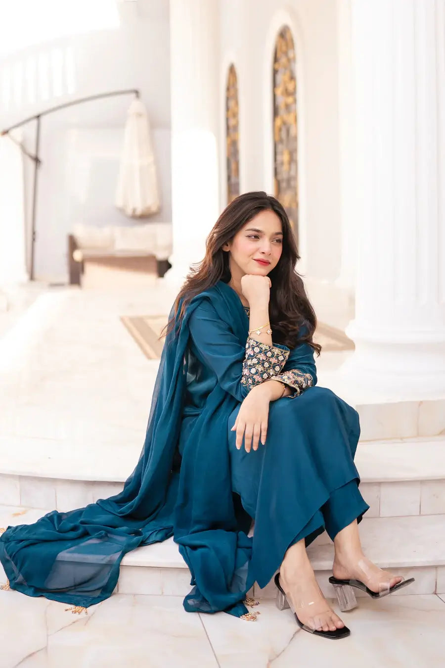 Woman in a blue traditional outfit sitting on a marble staircase.