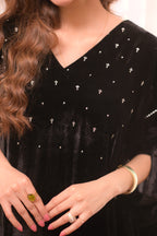 Black velvet dress with silver embellishments worn by a person.