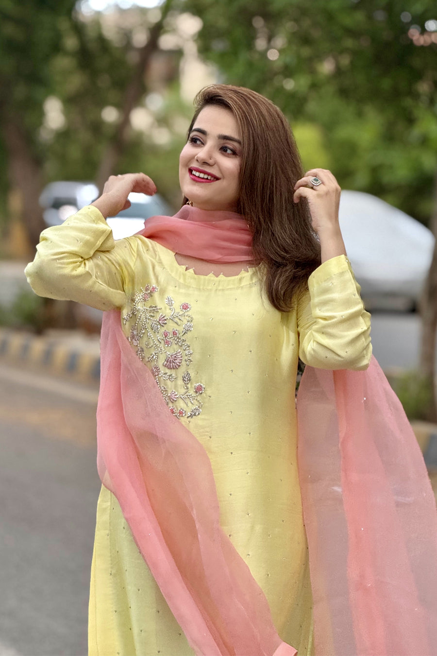 Woman in a yellow dress with pink dupatta standing outdoors