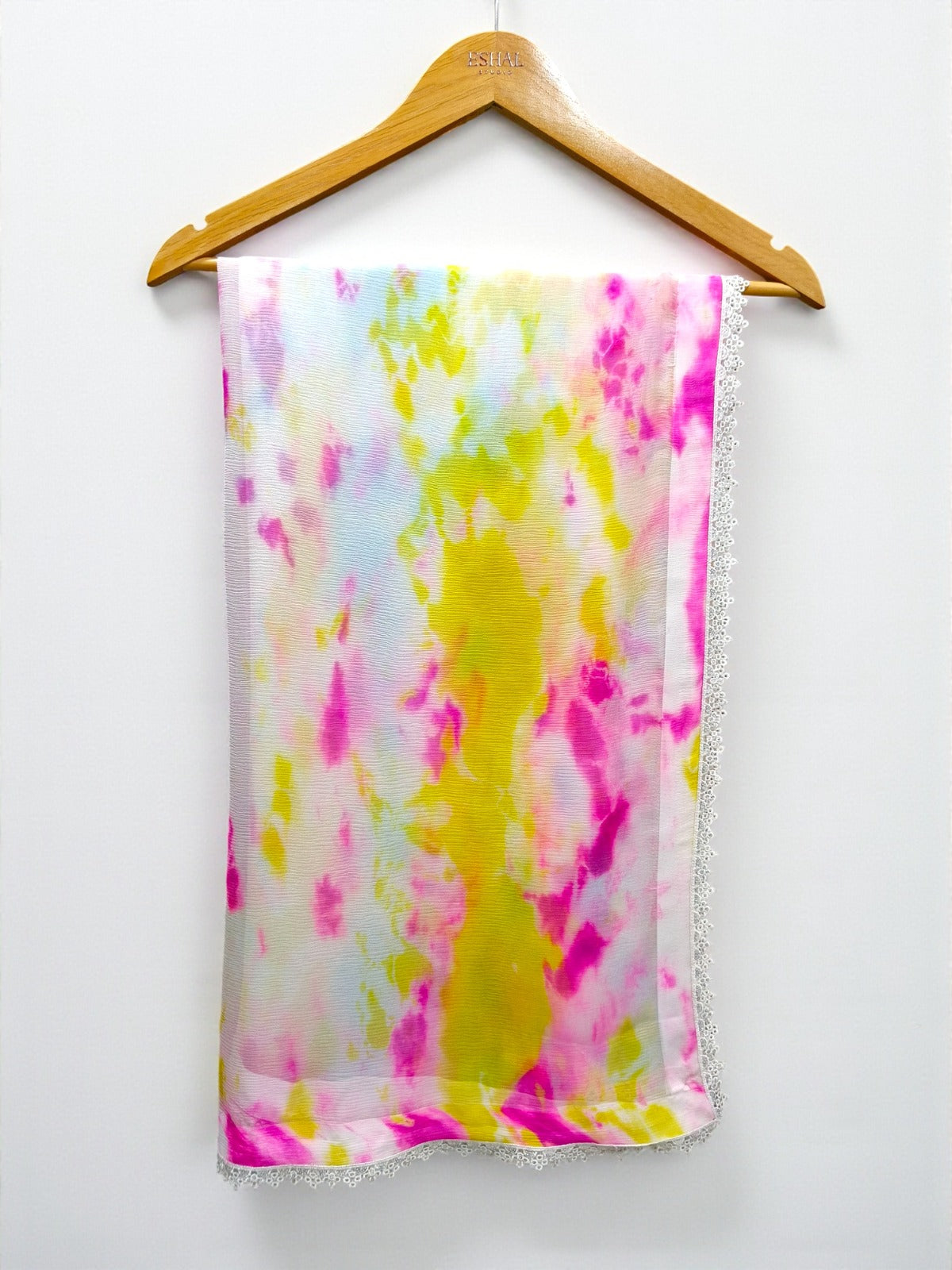 Colorful tie-dye fabric on a wooden hanger against a white background