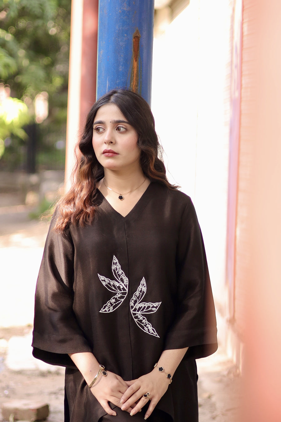 Woman wearing a black outfit with a white leaf design in an outdoor setting