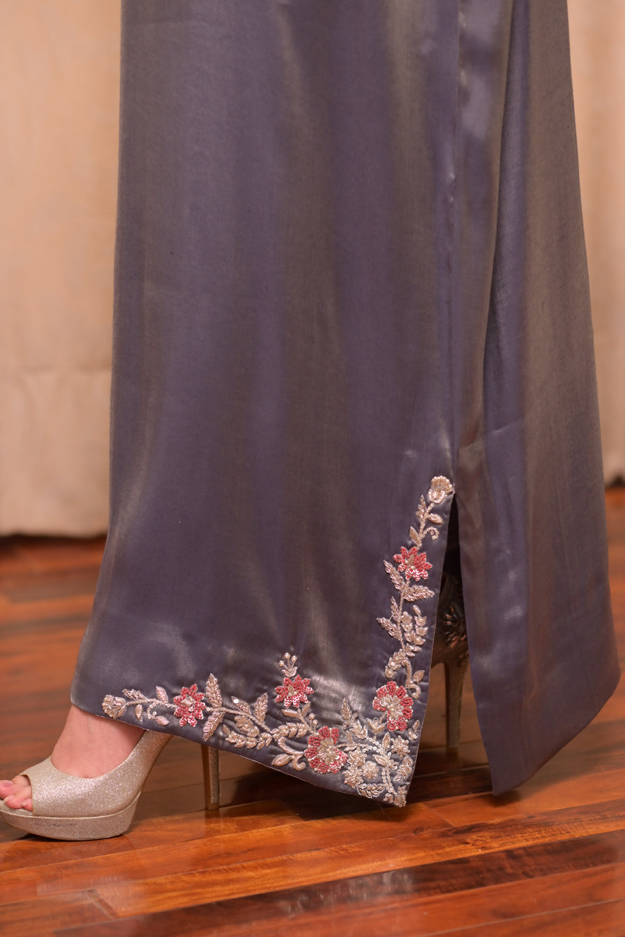 Navy blue satin fabric with floral embroidery on a wooden floor.