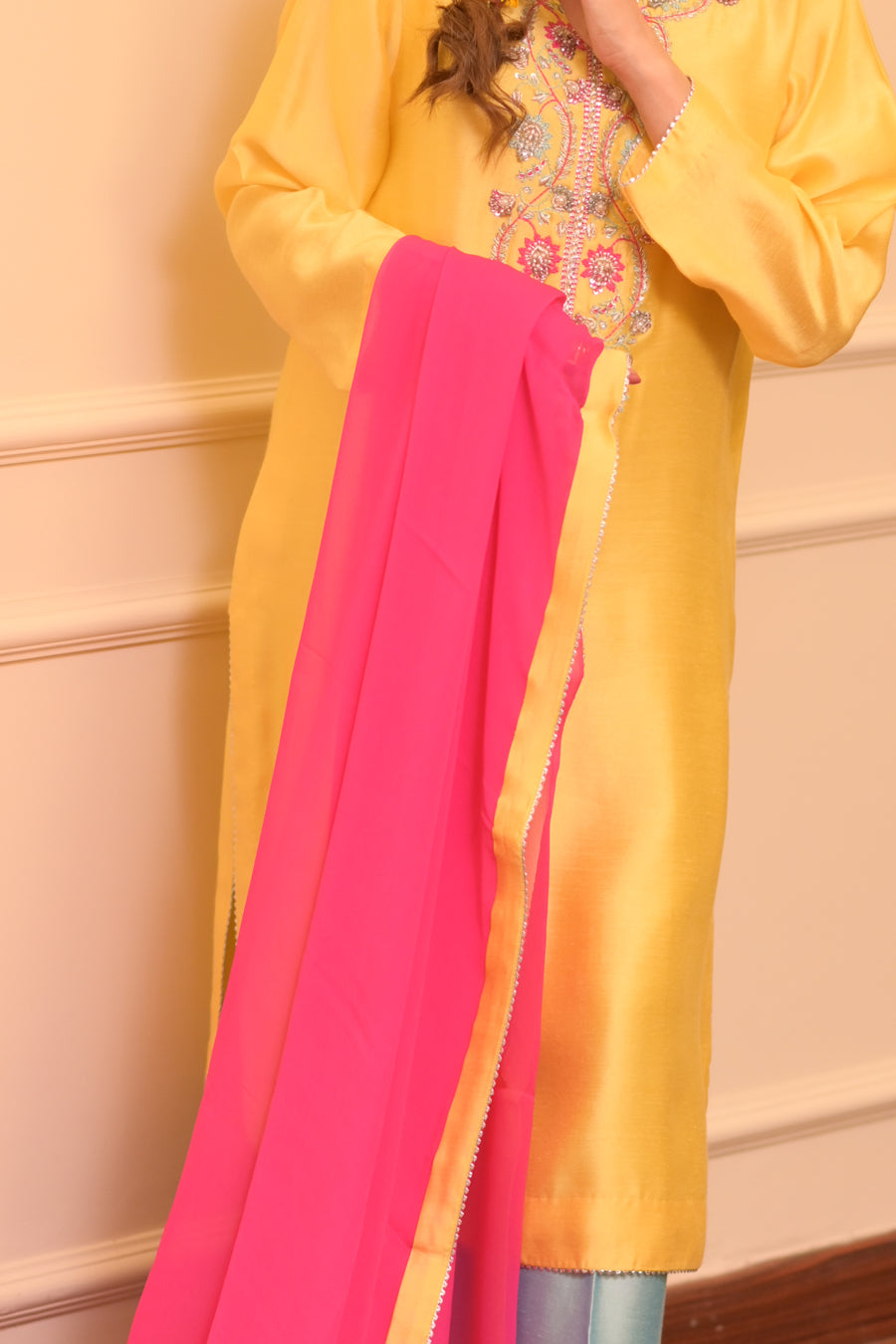 Yellow and pink traditional outfit with floral embroidery on a beige background