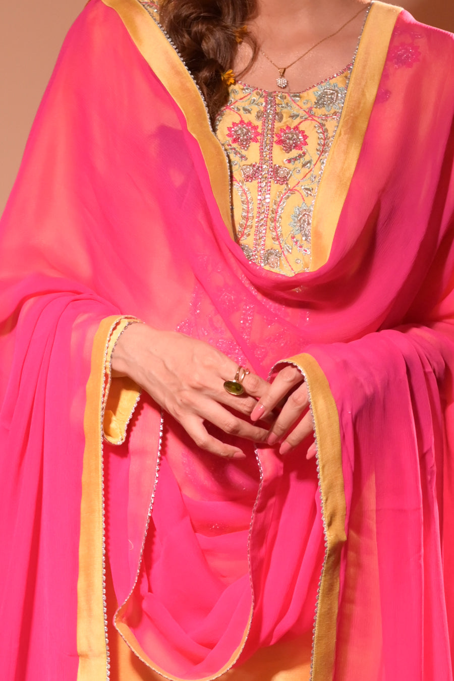 Person wearing a bright pink traditional outfit with intricate yellow embroidery