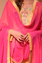 Person wearing a bright pink traditional outfit with intricate yellow embroidery
