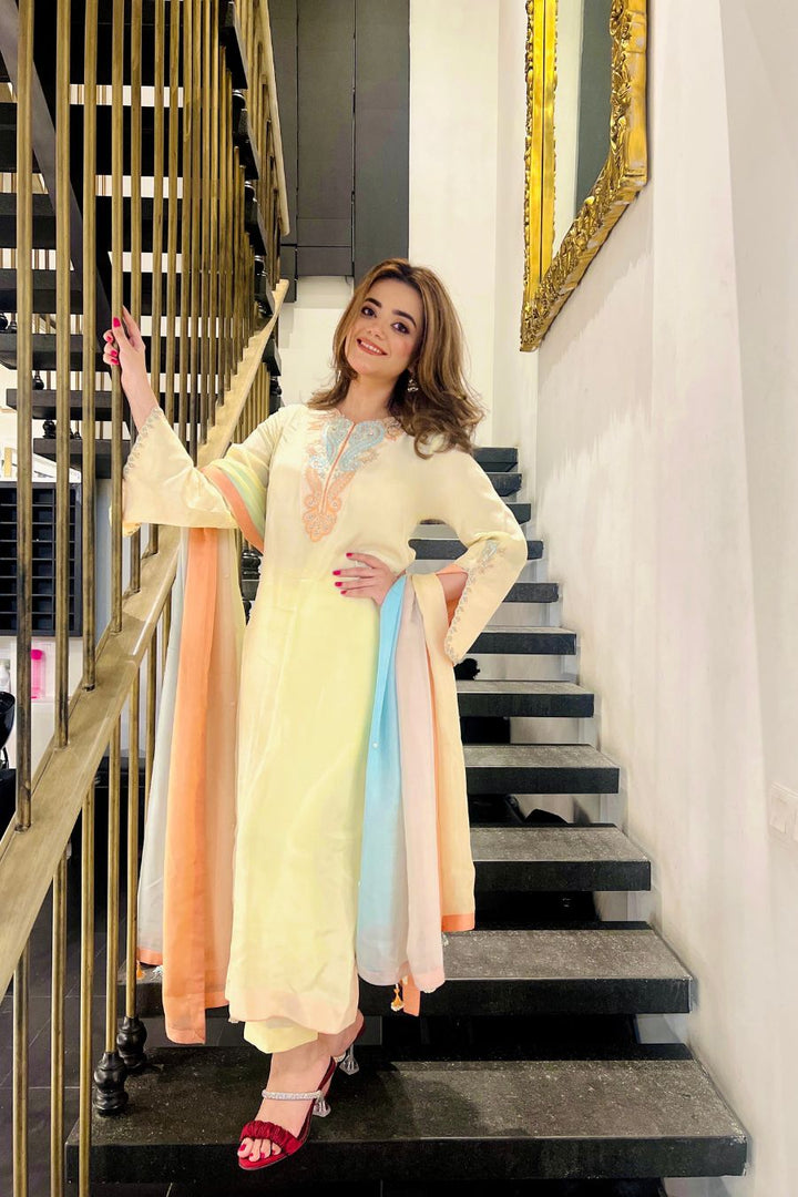 Woman in a pastel outfit standing on a staircase with a decorative wall in the background