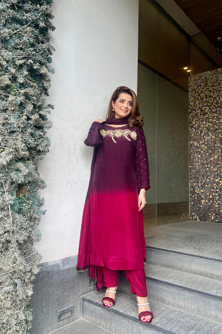 Woman in a purple and pink traditional outfit standing outdoors.