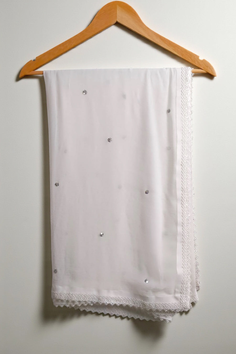 White scarf with black polka dots on a wooden hanger against a white background
