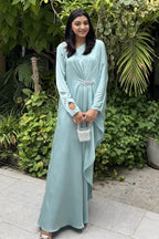 Woman in a light blue dress standing in front of green foliage